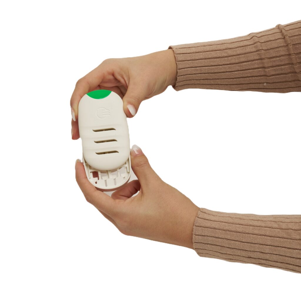 Two hands hold and open a Wilro Personal Waterless Vaporizer, a white device with a green button, against a white background. The person wears a long-sleeved, light brown ribbed top.