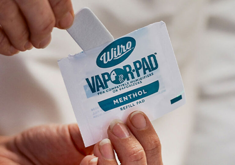 A person’s hands open a Wilro Vapor-Pad menthol refill pad package, holding the pad above the packet. The pad is designed for use in compatible humidifiers and vaporizers.